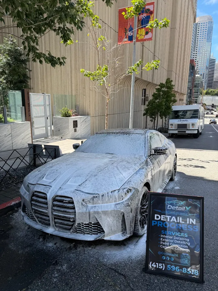BMW covered in snow foam during a mobile wash on a San Francisco street
